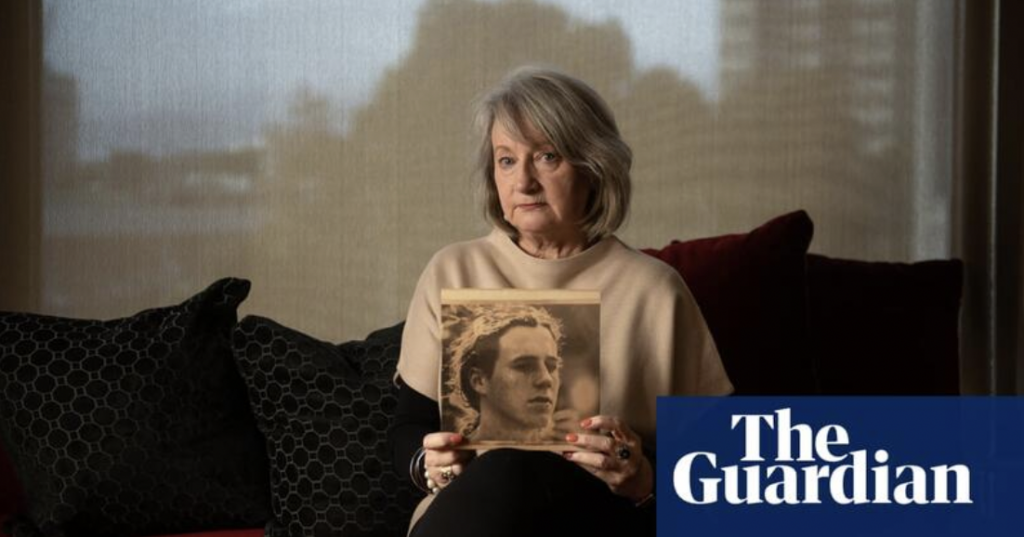 Older woman holds photo of young boy wile sitting on sofa