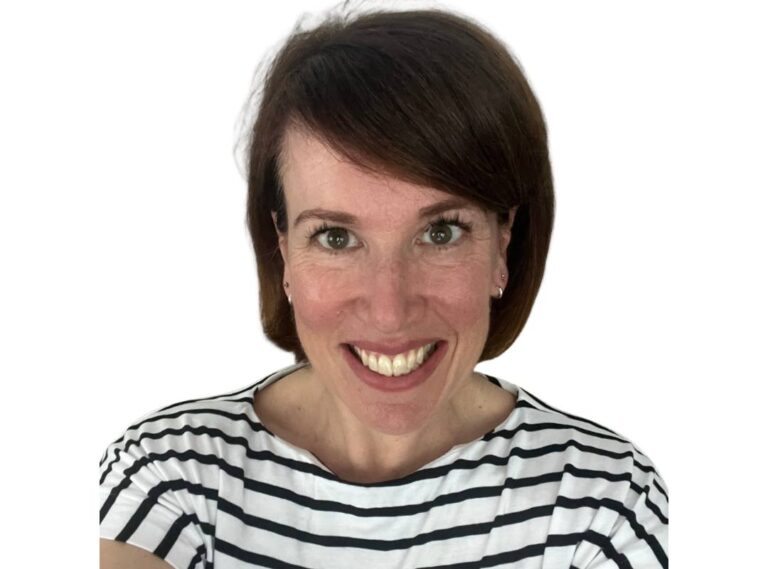 Andrea Pound wears a striped black and white top and is looking at the camera smiling.