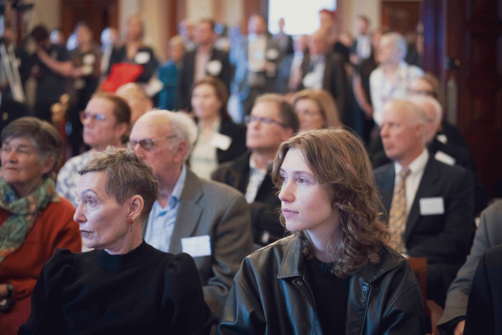 Rows of audience members listening intently to speakers